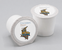 Thumbnail for A studio close-up view of two white single-serve coffee pods (K-Cup type), with one pod on its side and the other standing, both showing lids printed with the label 