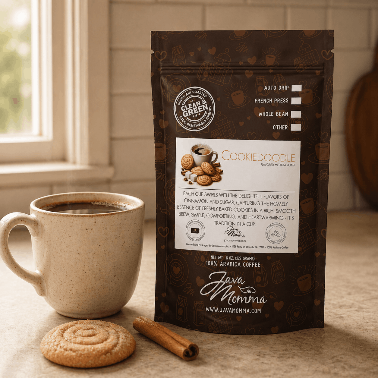 Java Momma Cookiedoodle coffee bag on a kitchen counter beside a rustic mug of black coffee, a cinnamon stick, and a baked snickerdoodle cookie.