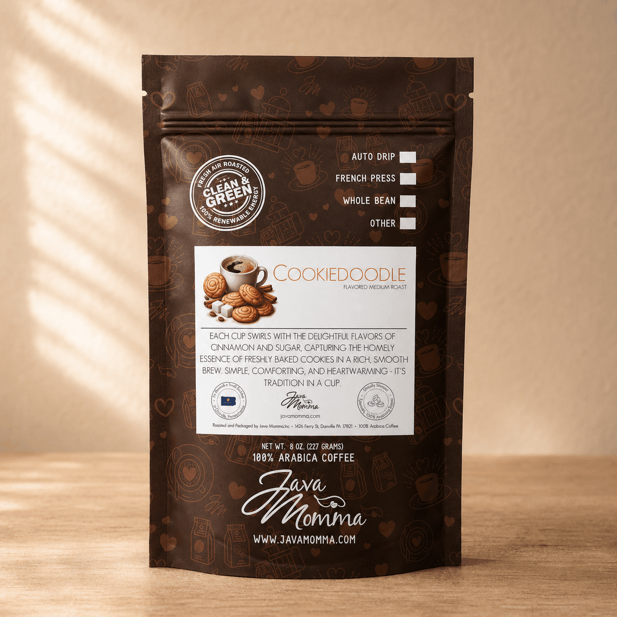 Front view of Java Momma Cookiedoodle flavored medium roast coffee bag standing upright on a wooden table with warm, dappled lighting.