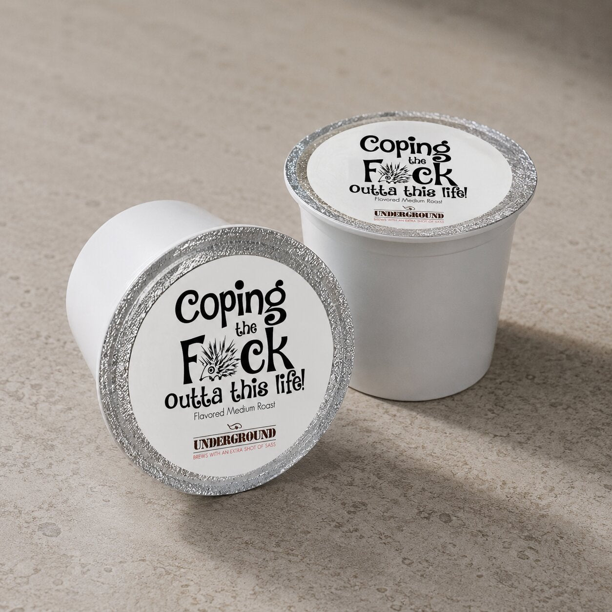 Two white coffee pods with black text on a beige surface