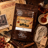Thumbnail for Cryptid Bacon Coffee | Momma's Picks bag with notes and coffee accessories in a rustic setting.