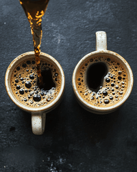 Thumbnail for Overhead view of two ceramic mugs with fresh-poured coffee on a dark slate surface — Java Momma Day/Night Duo