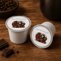 Thumbnail for Two 'Death By Chocolate' coffee pods on a wooden surface with chocolate pieces.