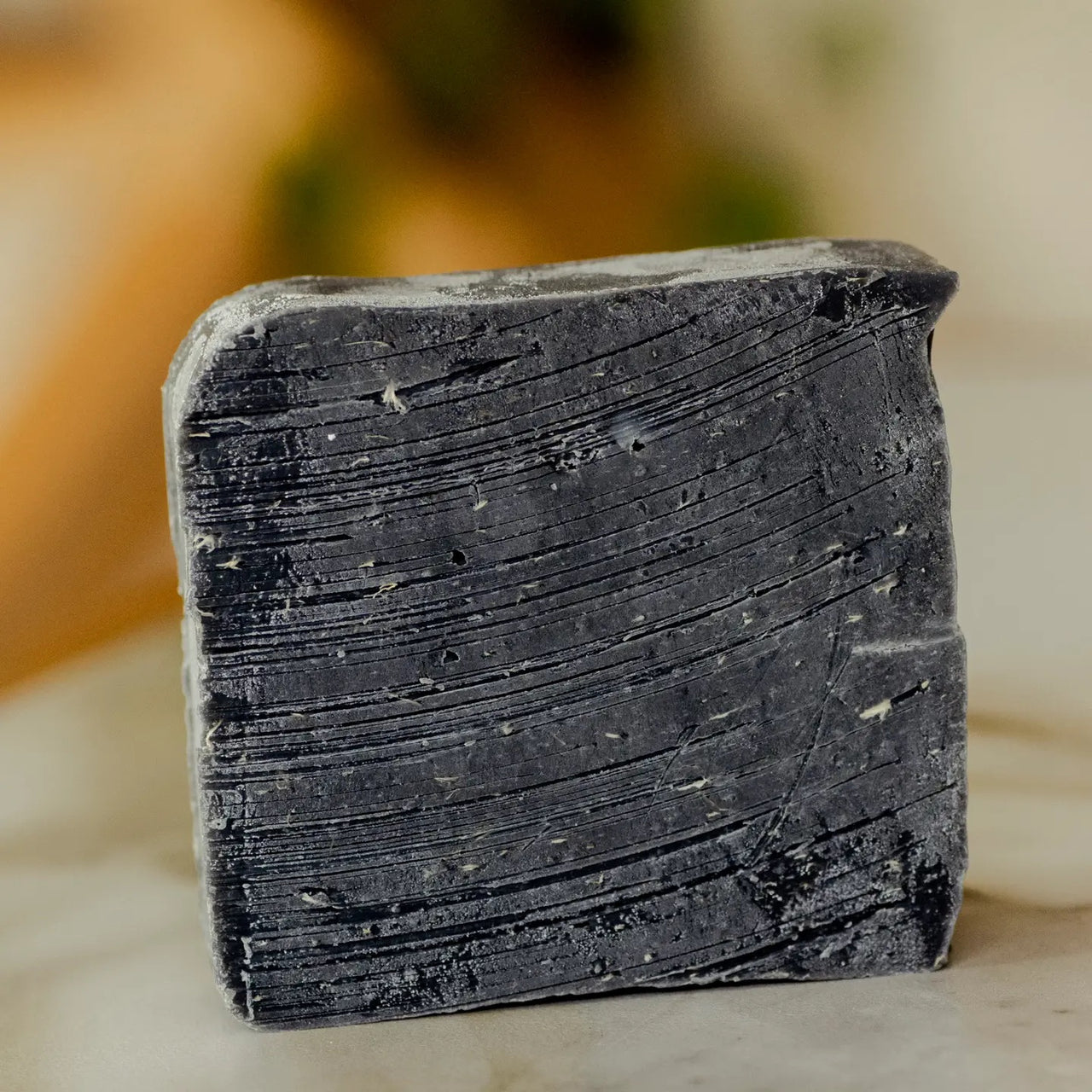 A close-up of the No Tox Life Underarm Detox – Deodorant Booster Cleansing Bar (19.3g), featuring textured lines and specks on a light surface—an ideal aluminum-free, natural deodorant alternative for a fresher feel.
