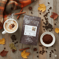 Thumbnail for Dirty Chocolate Chai Coffee package with a cup of coffee, coffee beans, and autumn leaves on a wooden surface.