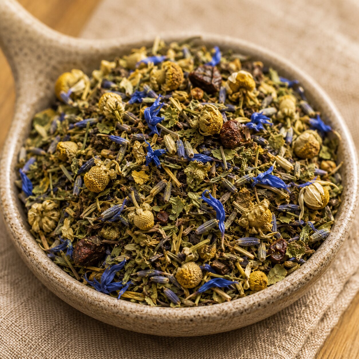 Dreamscape Herbal tea mix with dried herbs in a ceramic bowl on a textured surface