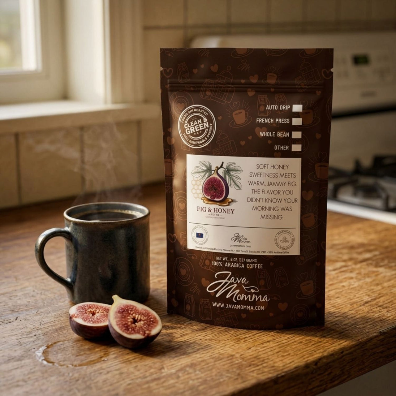 Java Momma Fig & Honey Coffee bag on a wood kitchen counter beside a steaming dark ceramic mug and two halved fresh figs