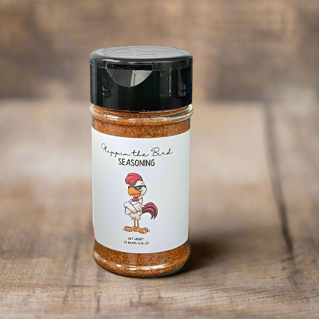 Flippin’ the Bird Seasoning jar with a cartoon chicken on the label, placed on a rustic wood background.