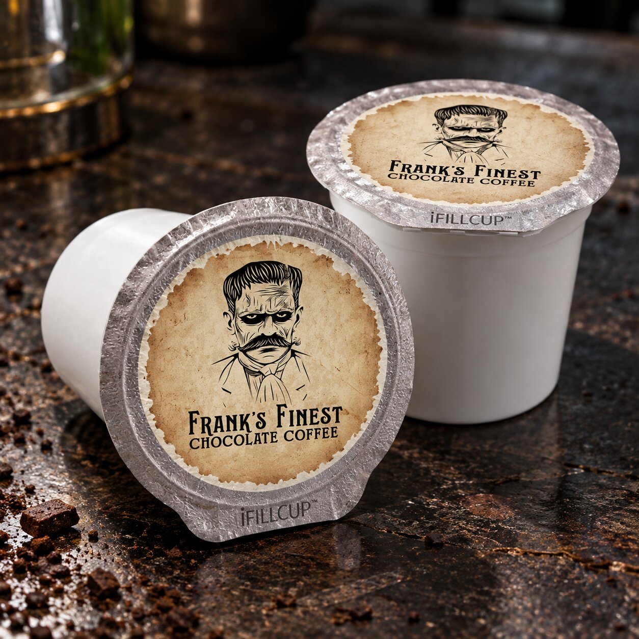 Two white coffee pods in foil cups on a dark countertop, with one pod lying on its side and the other standing upright. Both have tan circular labels reading "Frank's Finest Chocolate Coffee" with a black illustrated portrait and "iFILL CUP" near the bottom.