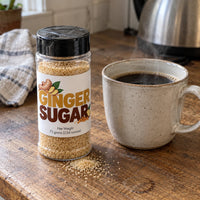 Thumbnail for Ginger Sugar Sprinkle jar next to a steaming mug of coffee on a wooden table for a delightful finishing touch.