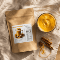 Thumbnail for A kraft paper stand-up pouch labeled Golden Chai Latte is arranged on a beige fabric surface beside a glass of golden iced latte, cinnamon sticks, star anise, and scattered turmeric powder.