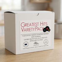 Thumbnail for White coffee pod variety pack box on a wooden surface with a blurred background Greatest Hits Variety Pack on label