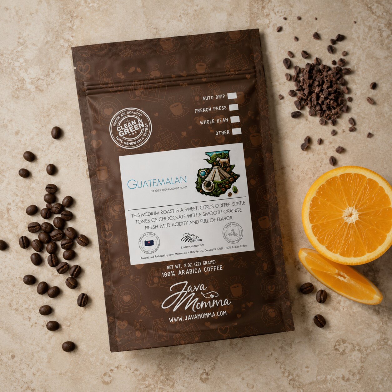 Overhead flatlay of Java Momma Guatemalan Medium Roast coffee bag with whole coffee beans, an orange slice, and cacao nibs