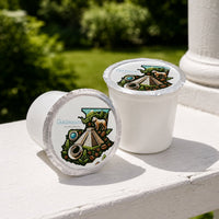 Thumbnail for Two white coffee pods with Guatemalan design on a white surface outdoors.