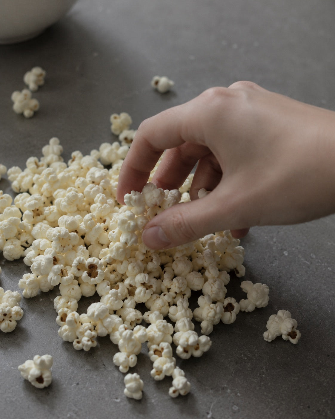 Hand reaching for popcorn on a dark surface