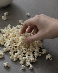Thumbnail for Hand reaching for popcorn on a dark surface