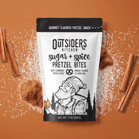 Thumbnail for A bag of Sugar + Spice Pretzel Bites – Sweet, Salty, and Straight-Up Craveable 🍬🔥 sits on a brown surface with sugar, cinnamon powder, and sticks. Made in small batches, the packaging features an illustrated bearded man holding a pretzel.