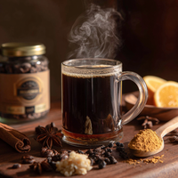 Thumbnail for A steaming glass mug of Highlander Grogg – Medium Roast Flavored Coffee sits on wood, surrounded by ground coffee, cinnamon, star anise, ginger, whole beans, and lemon slices. A jar of medium roast coffee beans appears in the background.