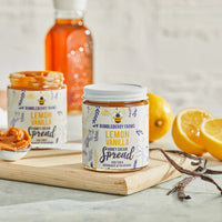 Thumbnail for A jar of Lemon Vanilla Honey Cream Spread 🍋–Tart, Sweet & Totally Irresistible–rests on a wooden board with another jar, lemons, vanilla bean, and wildflower honey. The open jar with a spoon invites you to taste its whipped delight.