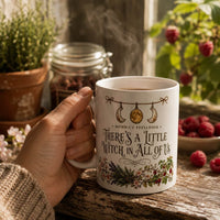 Thumbnail for There's a Little Witch in All of Us Mug with floral design, steaming coffee and rustic setting.