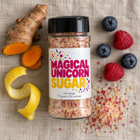 Thumbnail for A jar of Magical Unicorn Sugar Sprinkle surrounded by ingredients like turmeric, blueberries, and raspberries on a textile background.