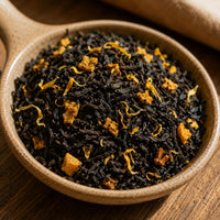 Thumbnail for Dry black tea leaves with gold elements in a ceramic bowl on a wooden surface