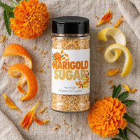Thumbnail for Marigold Sugar Sprinkle in a transparent jar with marigold petals and citrus peels on a textured background.