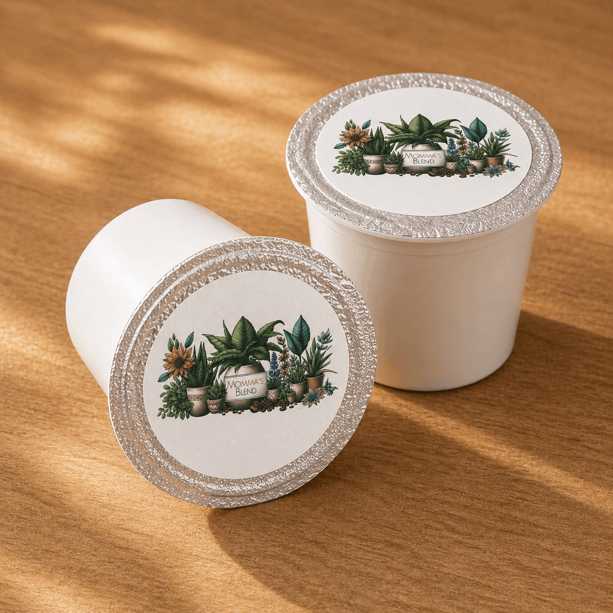 Two Java Momma Momma's Blend K-Cup pods on a warm wood surface with botanical label design visible on the foil tops