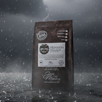 Thumbnail for A bag of Indian Monsoon Malabar Coffee | Dark Roast, Low Acid, Single Origin sits in the rain, highlighting its distinct single origin and renowned low acidity.