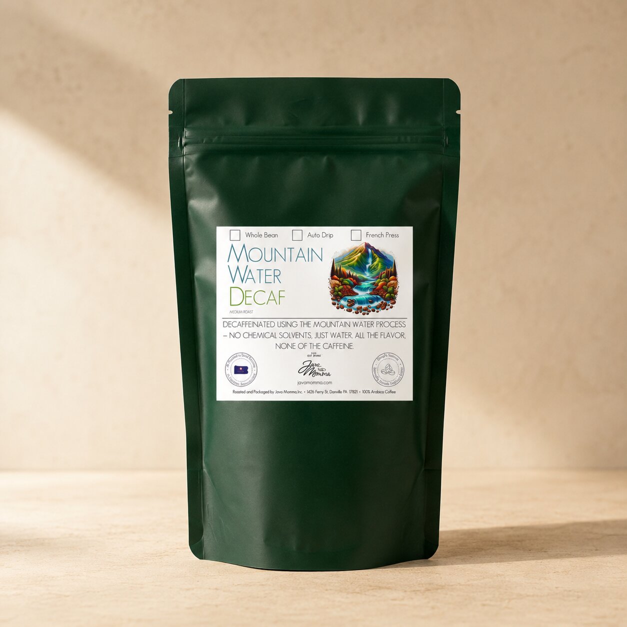 Green coffee bag labeled 'Mountain Water Decaf' from Java Momma
 on a beige background