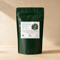 Thumbnail for Green coffee bag labeled 'Mountain Water Decaf' from Java Momma
 on a beige background
