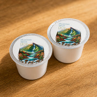 Thumbnail for Two Mountain Water Decaf coffee pods with scenic design on a wooden surface