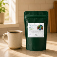 Thumbnail for Java Momma Decaf coffee package and cup on a wooden surface with a window in the background