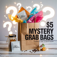 Thumbnail for A brown paper bag with colorful tissue, labeled packets, a jar, and a snack item surrounded by question marks. Text reads: Java Momma Mystery Grab Bags – $5 Sidewalk Sale Special with 2 surprise items inside.