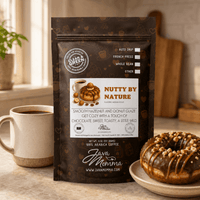 Thumbnail for Nutty by Nature coffee bag next to a ceramic mug with whole hazelnuts and a caramel drizzle on the side