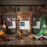 Thumbnail for Three bags from the Momma’s Picks Monthly Coffee Box—3 exclusive flavored coffees—sit on a rustic wooden table in a warm kitchen, surrounded by candles, nuts, cherries, and magical swirling effects.