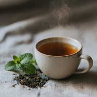 Thumbnail for Plot Twist Mint Tea | Darjeeling & Peppermint Black Tea Blend in a steaming cup with fresh mint leaves.