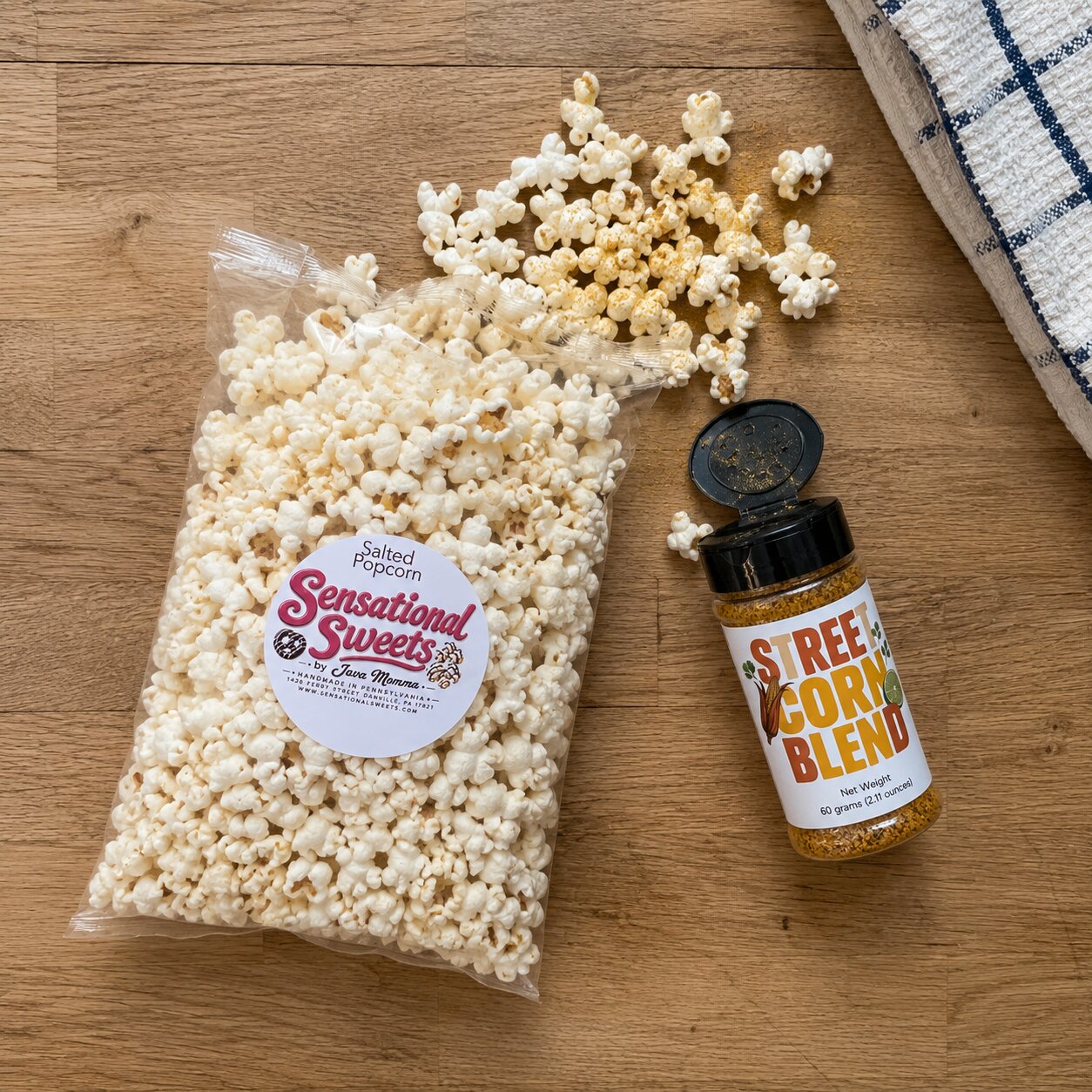 Bag of popcorn with a Sensational Sweets label and a bottle of Sweet Corn Blend seasoning on a wooden surface.