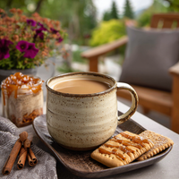 Thumbnail for A mug of Porch Swing Pickin’ flavored coffee—with notes of cinnamon, graham cracker, and butterscotch—sits on a plate with caramel-drizzled biscuits, cinnamon sticks, and flowers on an outdoor table with a blurred garden view.