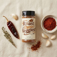 Thumbnail for Roast those Veggies Seasoning Blend jar with spices and garlic on a beige background, perfect for enhancing vegetable dishes.