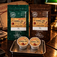 Thumbnail for Two bags of Roswell Red Coffee | Momma's Picks and coffee pods on a wooden table, highlighting caramel apple flavor.