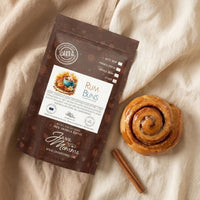 Thumbnail for Java Momma coffee package with a cinnamon roll and cinnamon stick on a beige fabric background