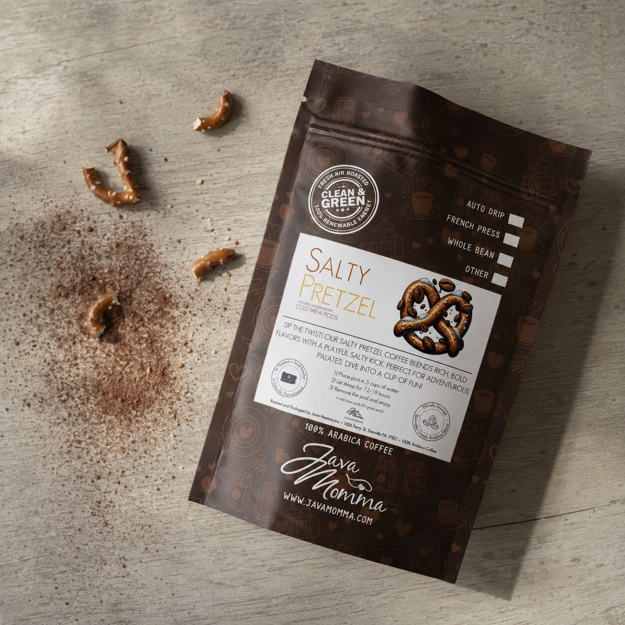 Overhead flatlay of Java Momma Salty Pretzel Cold Brew Pods bag with pretzel pieces and cocoa