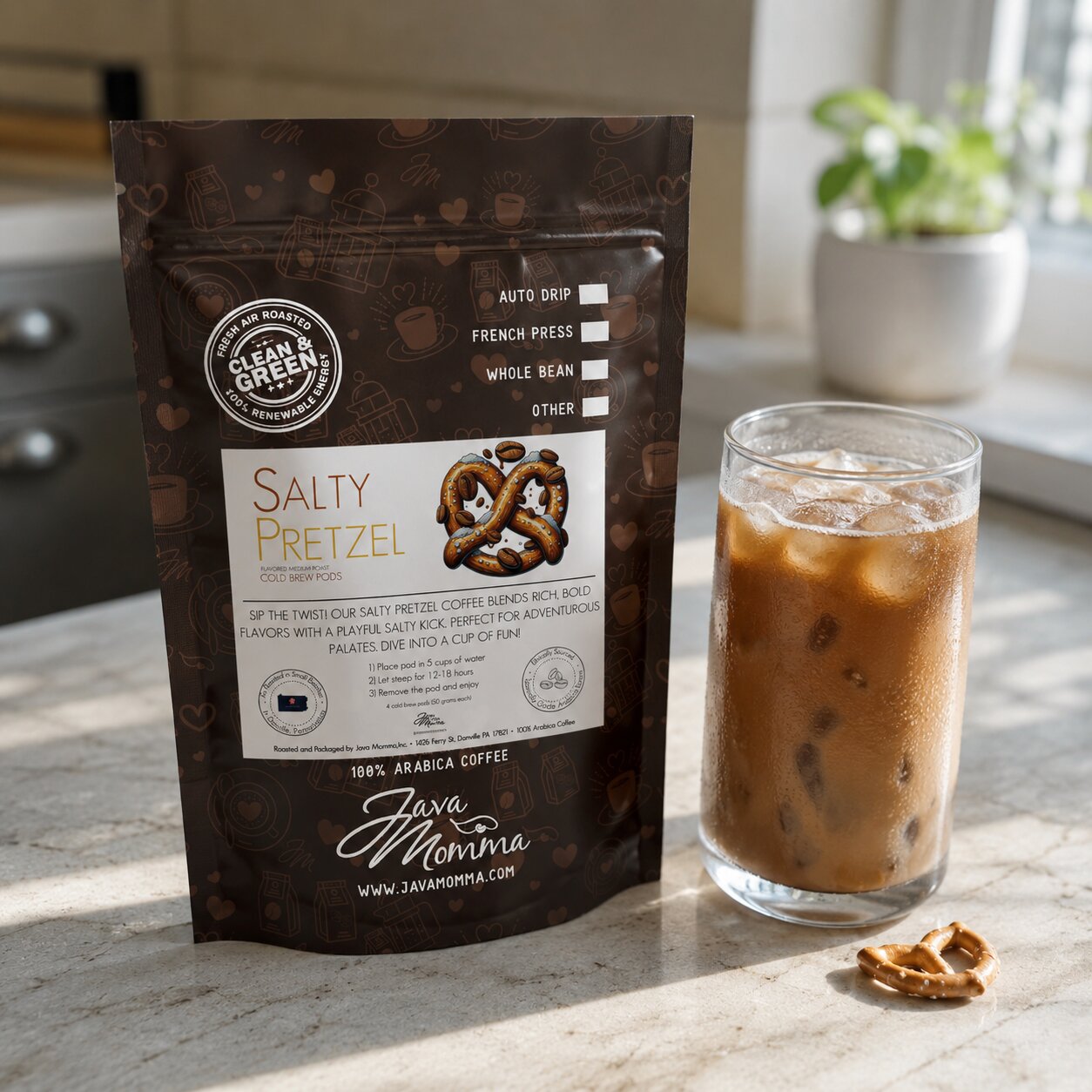 Java Momma Salty Pretzel Cold Brew Pods bag beside a glass of iced coffee with a pretzel piece