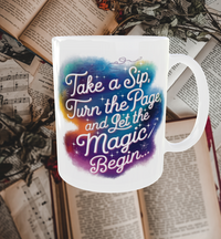 Thumbnail for A white ceramic mug featuring the quote 'Take a sip, turn the page, and let the magic begin' in whimsical, storybook-style lettering with a colorful gradient background. The mug sits on an open book, creating a cozy reading and coffee-drinking atmosphere.