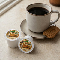 Thumbnail for Cup of coffee with a cookie on a saucer, accompanied by two coffee pods labeled 'Spiced Cookie Cream' on a neutral surface.