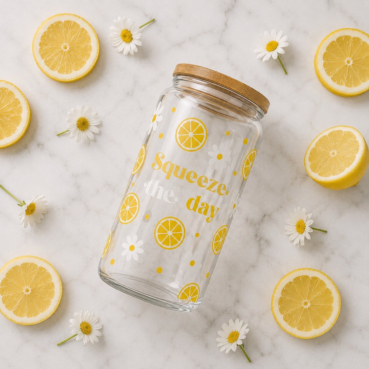 Glass jar with lemon designs and 'Squeeze the day' text on a marble background with lemons and daisies.