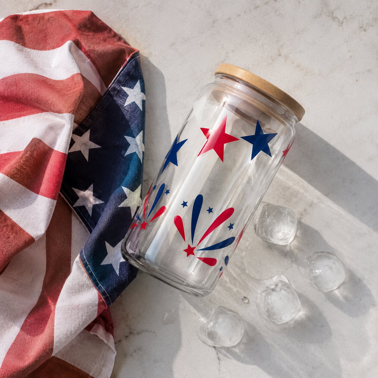Glass jar with star design next to an American flag and ice cubes on a light surface