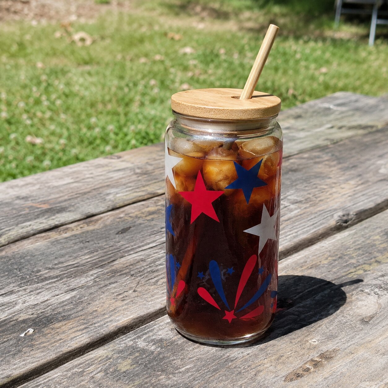Glass jar with iced coffee and star decorations on a wooden table outdoors