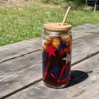 Thumbnail for Glass jar with iced coffee and star decorations on a wooden table outdoors